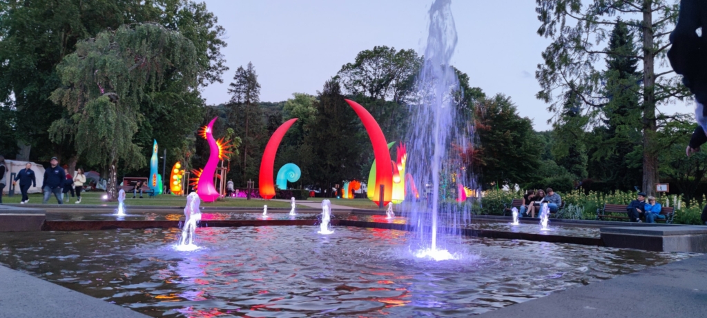 ein Wasserbrunnen mit bunten Skulpturen in der Mitte.