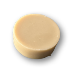 Ein rundes, beigefarbenes Seifenstück von WHISKER Rasierseife ruht auf einem schlichten weißen Hintergrund.