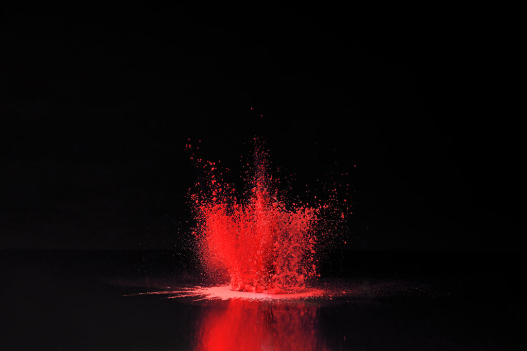 Ein Spritzer rotes Pulver auf schwarzem Hintergrund.