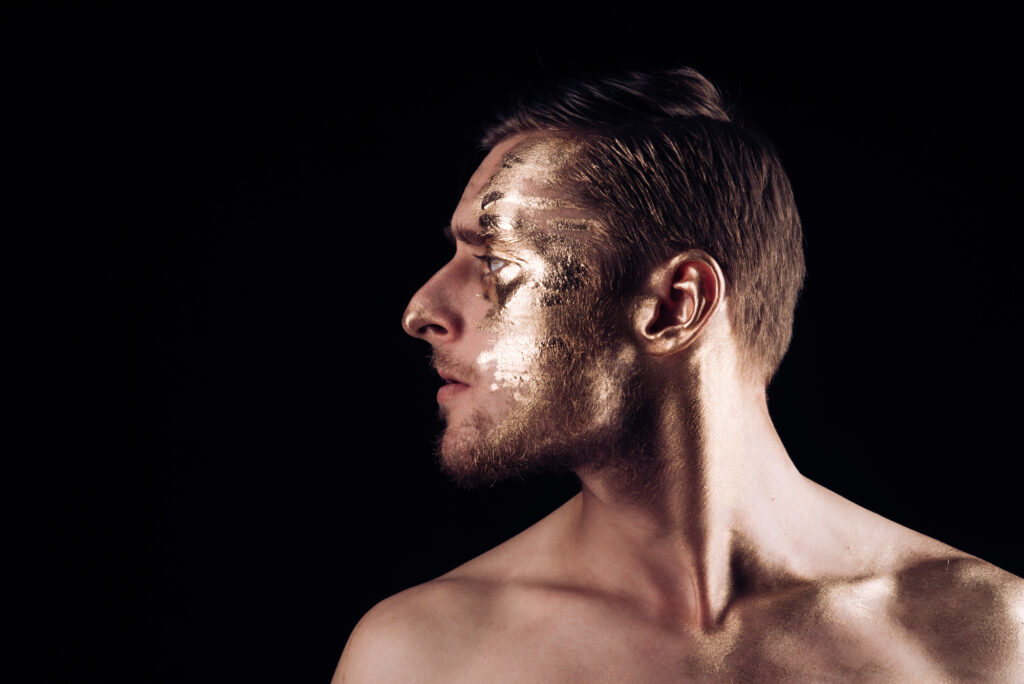 Ein Mann mit goldener Farbe im Gesicht.