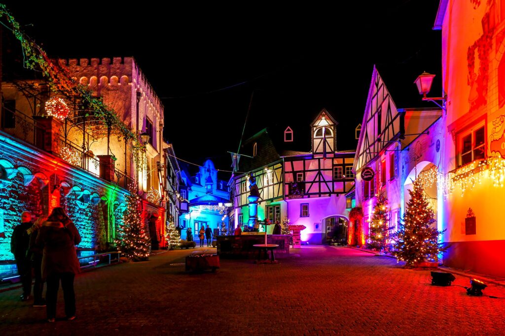 Zwei Menschen gehen eine mit Weihnachtsbeleuchtung beleuchtete Straße entlang.
