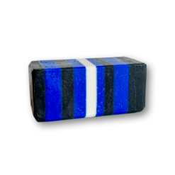 Ein rechteckiges Stück Chap-Seife mit abwechselnden horizontalen Streifen in Schwarz, Blau und Weiß vor einem schlichten weißen Hintergrund.