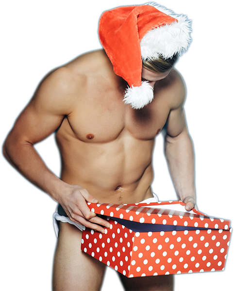 Ein Mann ohne Hemd, der eine Weihnachtsmannmütze und einen weißen Slip trägt, hält eine rot-weiß gepunktete Geschenkschachtel in der Hand und schaut hinein, vielleicht in der Hoffnung, darin ein luxuriöses Seife zu finden.