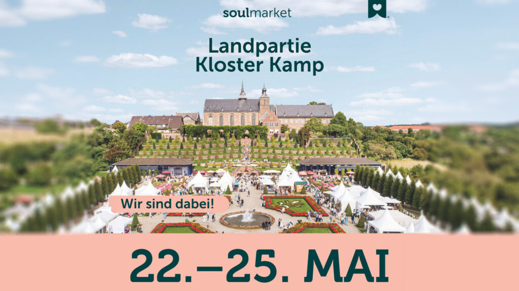 Vor dem Kloster Kamp ist ein Fest mit weißen Zelten und Besuchern aufgebaut, das vom 22. bis 25. Mai mit Texten für die Veranstaltung wirbt.